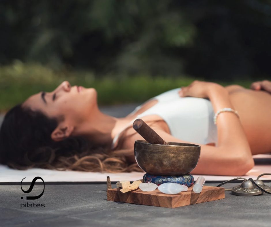 Mindful breathing and relaxation – woman lying on a mat beside a singing bowl